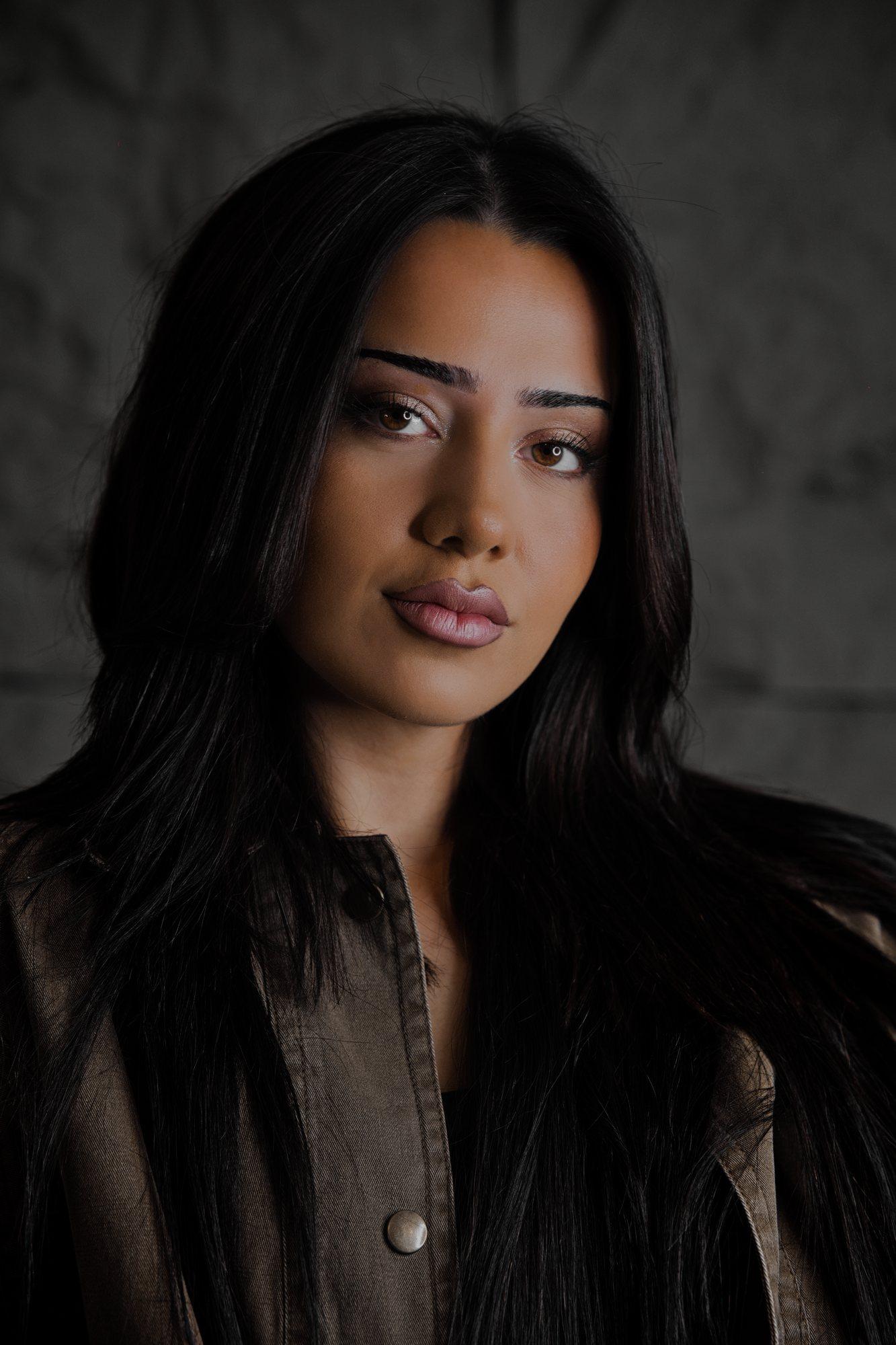 Portrait en studio sur fond sombre, teint sculpté et regard souligné
