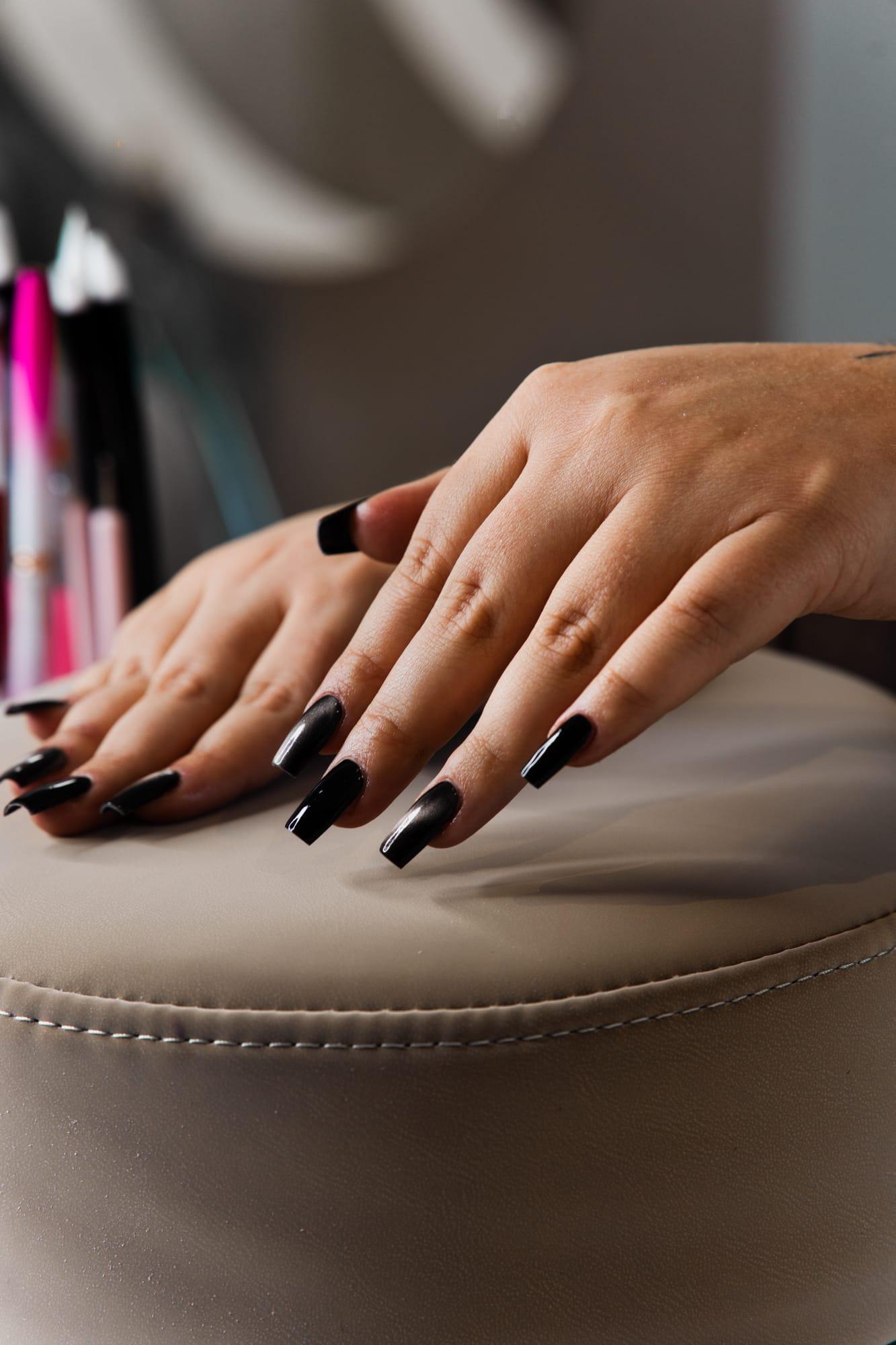 Ongles noirs forme amande, main posée sur le coussin