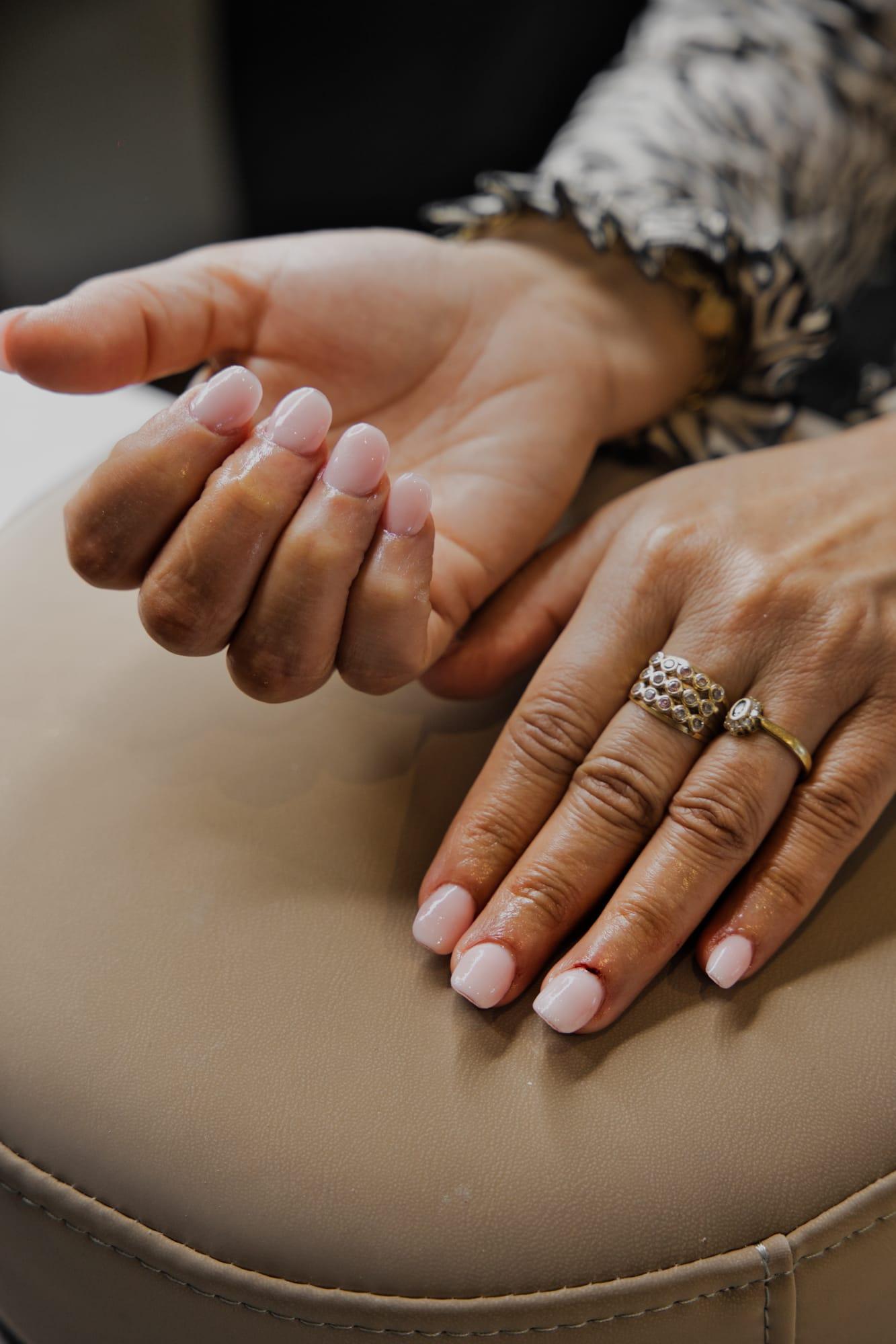 Ongles nude courts, mains ornées de bagues